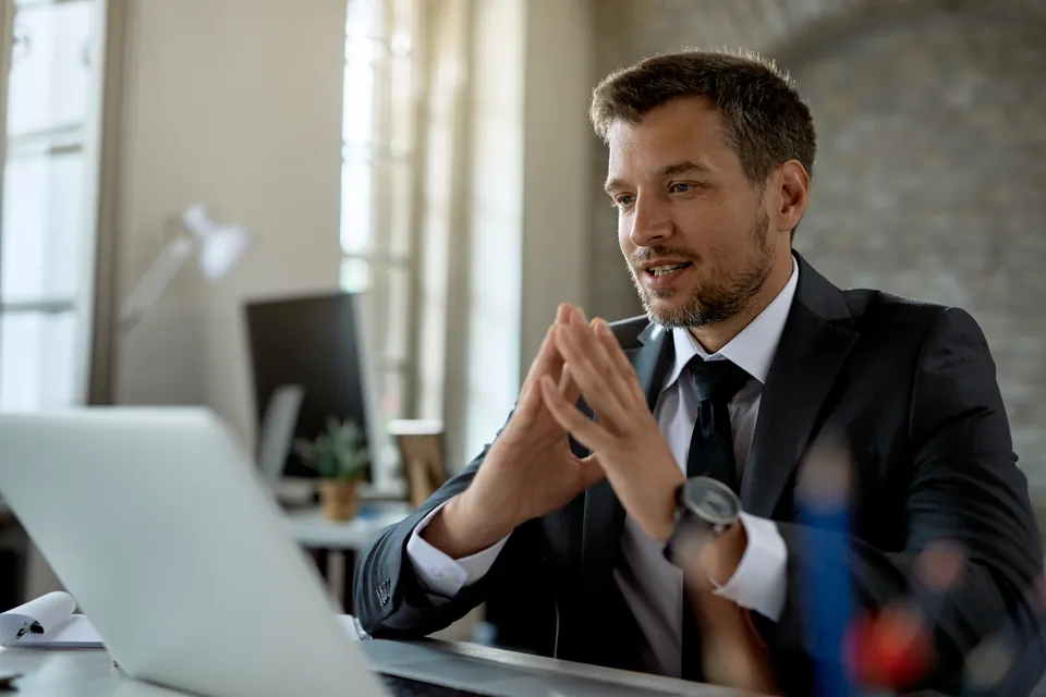 A man speaking during a video meeting at his desk